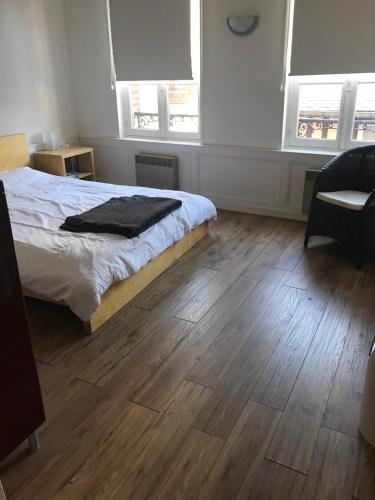 - une chambre avec un lit, du parquet et des fenêtres dans l'établissement Rue Des Lingots Apartment, à Honfleur