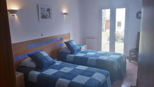 a bedroom with two beds with blue sheets and a window at Garden Apartment Quinta do Morgado in Tavira