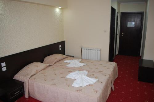 a hotel room with a bed with towels on it at Хотел Хилез Hotel Hilez in Tryavna
