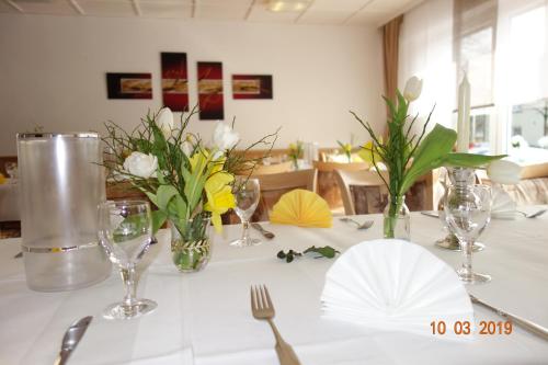 a white table with vases and flowers on it at Hotel Wiedenhof in Hilden