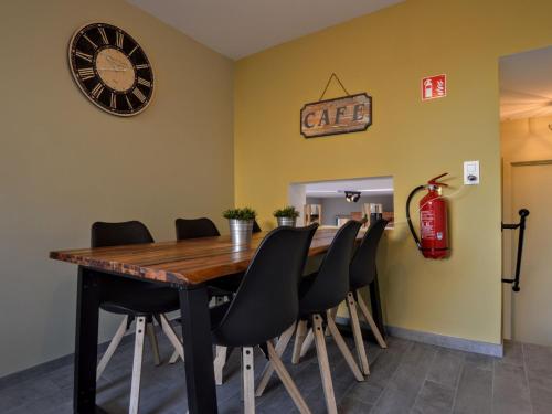 une salle à manger avec une table, des chaises et une horloge dans l'établissement Luxurious Cottage in Aywaille with Sauna, à Aywaille