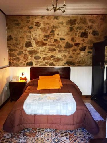 a bed in a room with a stone wall at Albergue-Hostel Casa da Gandara in Boimorto