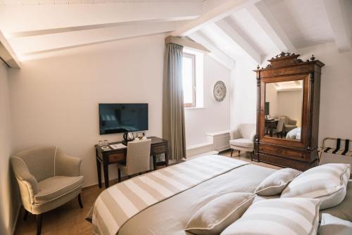 1 dormitorio con cama, silla y espejo en Giardini Calce - Luxury Rooms, en Ravello