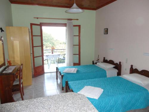 a bedroom with two beds and a balcony at Stamatela Studios in Paleokastritsa