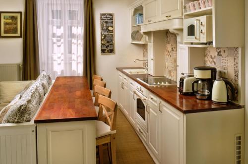 eine Küche mit weißen Schränken und einer hölzernen Arbeitsplatte in der Unterkunft Melody Apartman in Eger
