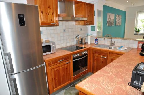 a kitchen with wooden cabinets and a stainless steel refrigerator at Apartmenthaus am Zimmerplatz in Hofheim am Taunus