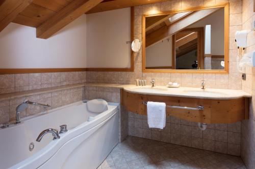 a bathroom with a tub and a sink and a mirror at Miramonti Park Hotel in Bormio