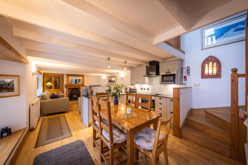 cocina y sala de estar con mesa de madera y sillas en The Barn Culnacnoc, en Culnacnoc