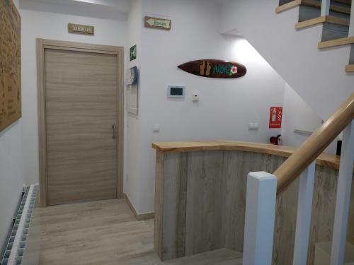 a hallway with a wooden door and stairs at Albergue La Magia del Camino in Comillas