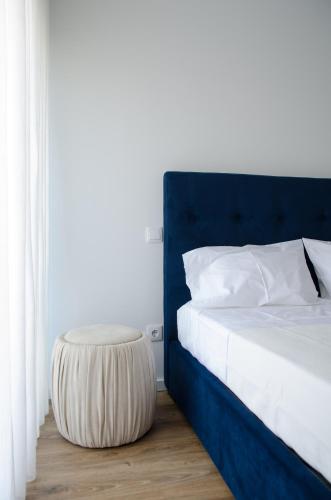 a bed with a blue headboard and a stool next to it at Antónia's house in Ponte de Lima