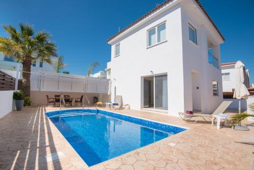 a villa with a swimming pool in front of a house at Narcissos Villa Doria in Protaras