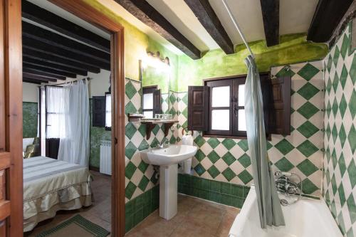 y baño con lavabo y paredes de azulejos verdes y blancos. en POSADA RURAL SIERRA de IBIO, en Villanueva de la Peña