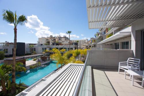 an apartment balcony with a swimming pool and palm trees at Opera Exclusive Apts by TrulyCyprus in Limassol