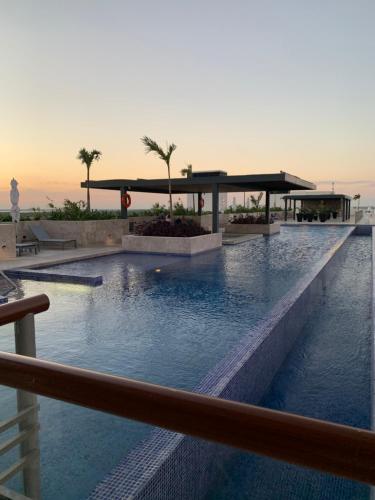 a pool at a resort with a sunset in the background at La Amada condo with Marina View in Cancún