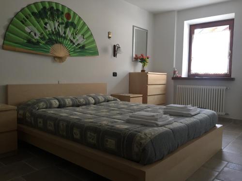 1 dormitorio con 1 cama con una pintura verde en la pared en Casa Luigina, en Comano Terme