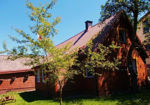 a red house with a tree in front of it at Bogdanówka in Supraśl