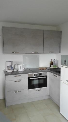 une cuisine avec des appareils en acier inoxydable et des armoires blanches dans l'établissement La Petite Maison de Marie Louise, à Lauris