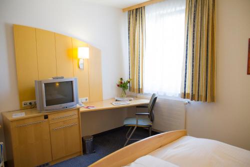 a hotel room with a desk with a tv and a bed at Gastwirtschaft & Hotel Holzinger in Möllersdorf