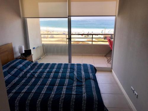 a bedroom with a bed and a view of the beach at Condominio Bordemar Los Molles in La Ligua