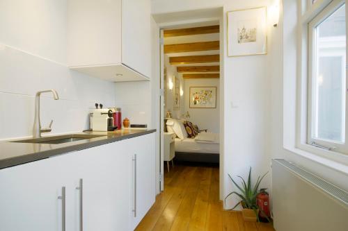 a kitchen with white walls and a sink and a window at Mercedes Bed&Breakfast Amsterdam in Amsterdam