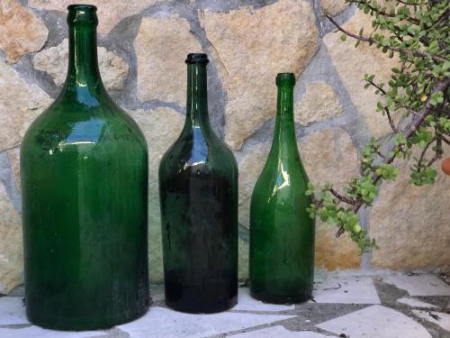 three green bottles sitting next to a stone wall at La Casetta di Eli in Siracusa