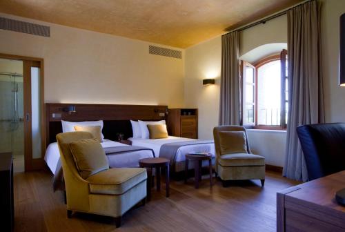 a hotel room with a bed and two chairs at Abadia Retuerta LeDomaine in Sardoncillo