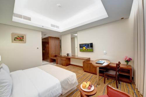 a hotel room with a bed and a desk and a table at Center Hotel Sharjah in Sharjah