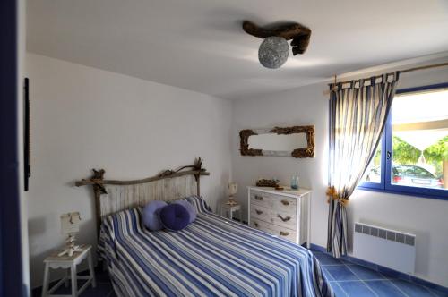 a bedroom with a bed and a dresser and a window at Résidence U MELU Grand T2 BLEU en rez de jardin in Tiuccia