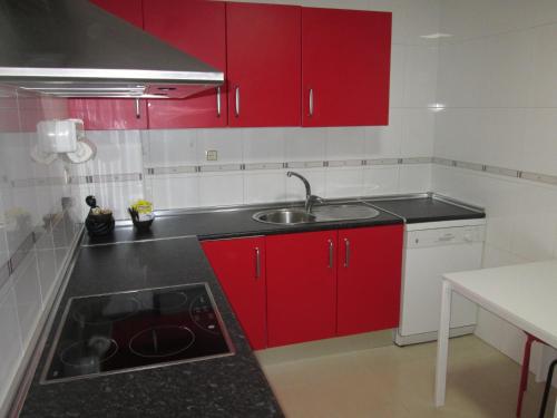una cocina con armarios rojos y fregadero en Piso Tesa, en Arévalo