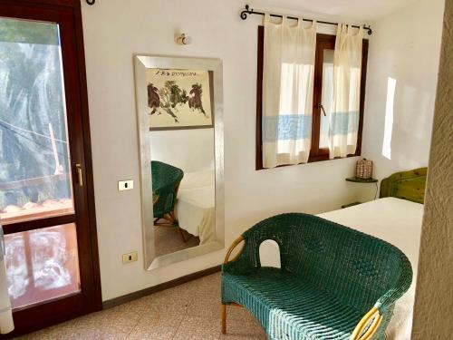 a bedroom with a green chair and a mirror at Villa Bianca in Capitana