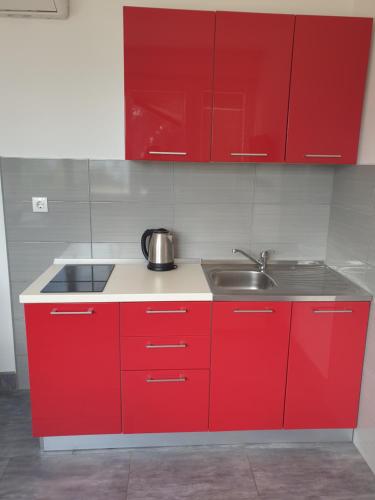 a red kitchen with a sink and red cabinets at Guest House Matana in Sobra