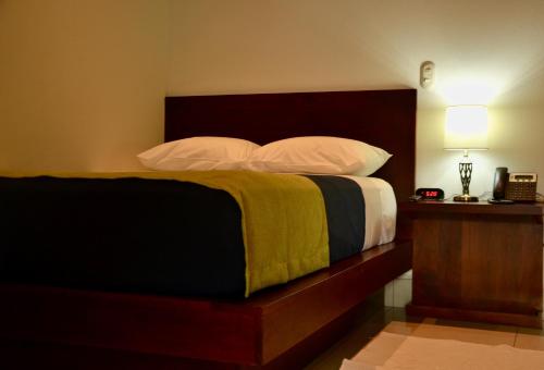 a bedroom with a bed with a wooden headboard and pillows at Hotel Agualcas in Managua