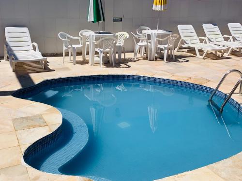 a large swimming pool with chairs and a table at Pousada Paradise in Alcobaça