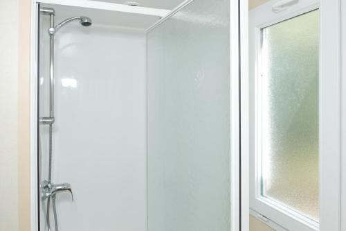 una ducha con una puerta de cristal junto a una ventana en Chalet Arran en Enscherange