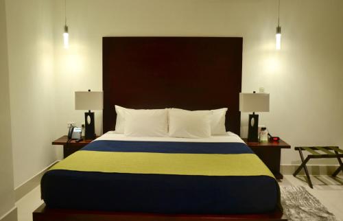 a bedroom with a large bed with two tables and two lamps at Hotel Agualcas in Managua