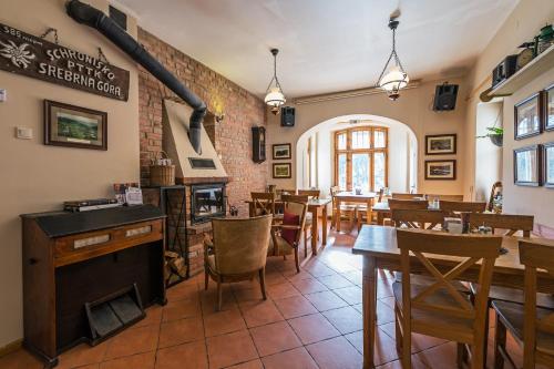 a restaurant with tables and chairs and a fireplace at Villa Hubertus in Srebrna Góra