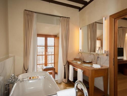 a bathroom with a tub and a sink and a mirror at Abadia Retuerta LeDomaine in Sardoncillo