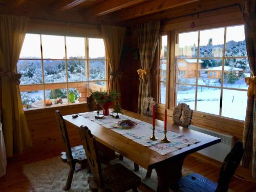 a dining room with a wooden table and windows at Vytina log house in Vytina