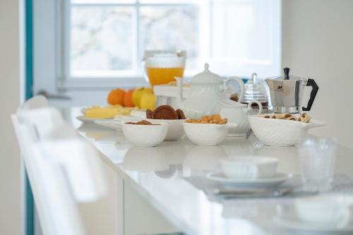 a white counter with bowls of food on it at Abrigo da Cascata - Casas de Campo - São Jorge in Calheta