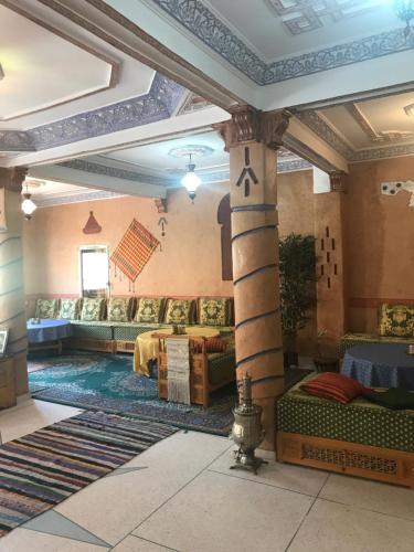 a living room with a pillar and couches in a room at Auberge Restaurant Zahra in Boumalne