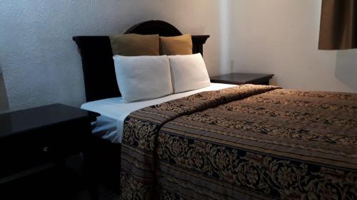 a hotel room with a bed with two pillows at Hotel Don Quijote in Mexicali