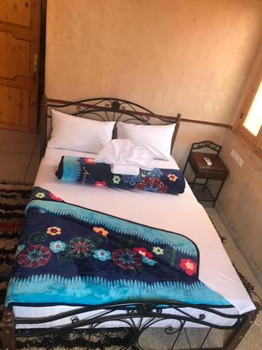 a bed with two pillows and a blanket on it at Auberge Restaurant Zahra in Boumalne