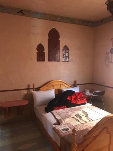 a bedroom with a bed in a room with two windows at Auberge Restaurant Zahra in Boumalne