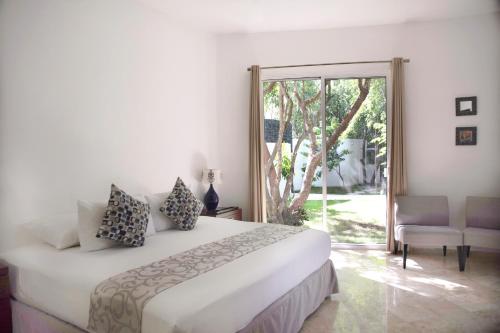 Dormitorio blanco con cama y puerta corredera de cristal en Coco Village, en Tulum