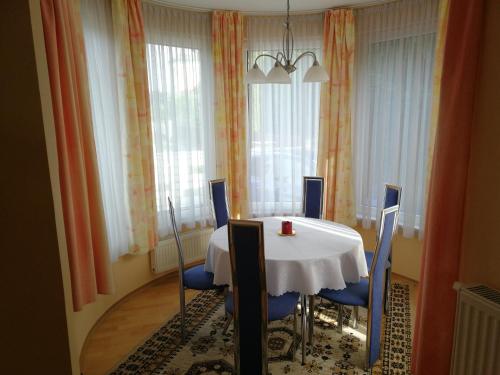 ein Esszimmer mit einem weißen Tisch und blauen Stühlen in der Unterkunft Sunshine Beach House in Szántód