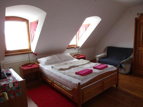 a bedroom with a bed with two windows and a chair at Királyszéke Apartman in Eger