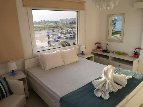 Schlafzimmer mit einem Bett und einem großen Fenster in der Unterkunft Bettys 1br seafront apt in Larnaka