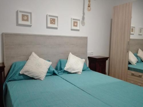 1 dormitorio con 1 cama verde y 2 almohadas blancas en Sa Cala Beach House, en Cala Figuera