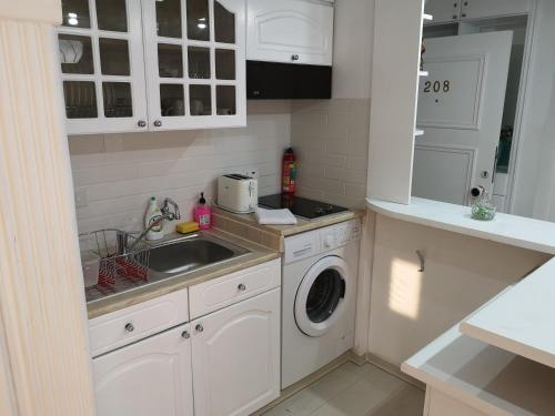 cocina blanca con fregadero y lavadora en Bettys 1br seafront apt, en Lárnaca