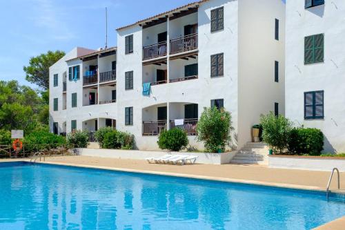 un edificio con piscina en frente de un edificio en Vistas al mar y la piscina, en Arenal d'en Castell